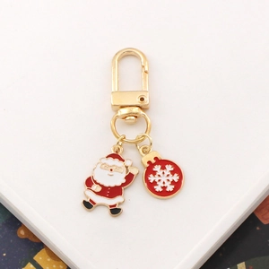 Close-up of golden Santa Claus and red snowflake metal keychain with enamel coating