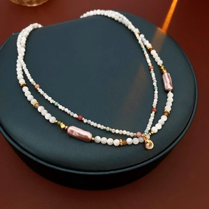 Close-up of double-layered beaded necklace with white pearls and gold pendant