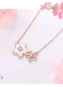 Detail of rose gold cherry blossom necklace featuring white shells and zircon stones