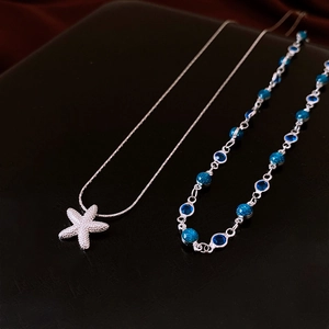 Détail d'un collier pendentif étoile de mer argenté avec perles bleues foncées
