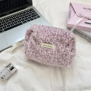 Detailed close-up of pink leopard plush makeup bag with soft texture and ribbon zipper