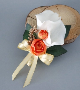 Detail of white calla lily and orange rose boutonniere with gold berries and ribbon