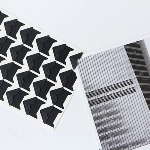 Close-up of black self-adhesive photo corners fixing a vintage photo on a white background
