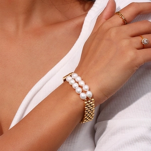 Detail view of double-row white pearls with golden metal accents on a stylish bracelet