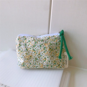 Close-up of small floral cotton pouch with green braided zipper pull and simple wish label