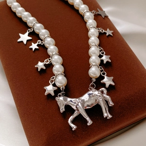 Detail shot of pearl necklace with silver star pendants and an elegant horse charm