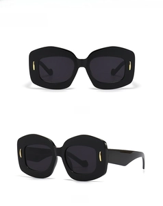 Front and side view of black irregular polygonal sunglasses with gold metal accents