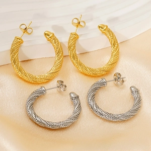 Close-up of 18K gold and silver twisted rope hoop earrings on champagne satin