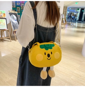 Detail of yellow persimmon cartoon canvas bag with plush legs worn as a crossbody