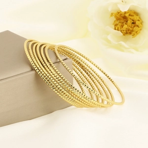 Set of 7 gold stackable stainless steel bangles with textured diamond cut finish