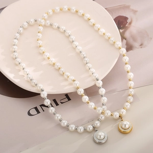 Close-up of pearl necklace with gold metal beads and a diamond-encrusted round pendant