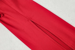 Detailed close-up of double-stitched slit on a red bodycon dress with woven texture
