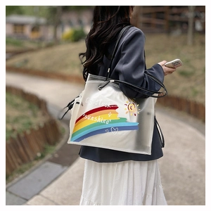 Outdoor shot of a transparent PVC beach tote with rainbow patterns and black handles