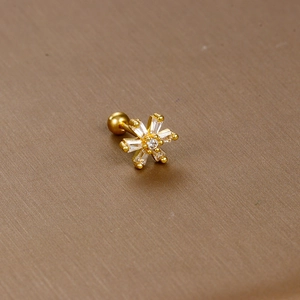 Macro shot of gold snowflake stud earring with baguette-cut zircons and ball back