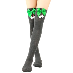 Detail of grey over-knee knitted socks featuring green satin bows and white fur pom-poms