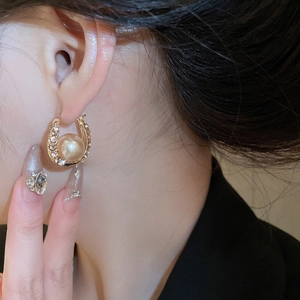Detailed close-up of a French style gold pearl earring with sparkling rhinestones on the ear