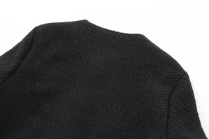 Close-up of premium black woven tweed fabric texture and precise stitching on female jacket