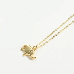 Close-up of golden elephant pendant with white rhinestone eye on a delicate chain