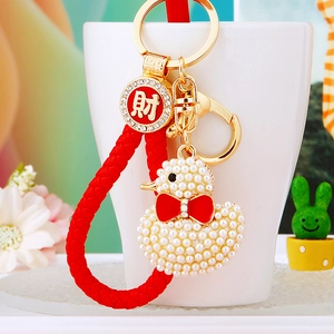 Detail of beaded duck keychain with red braided cord and a gold fortune lucky charm