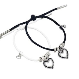 Close-up of woven black and white couple bracelets with rhinestone heart charms