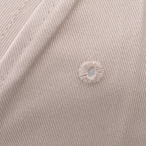 Macro shot of apricot cotton twill fabric with reinforced stitched embroidery eyelet