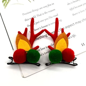 Cute pair of Christmas reindeer antler hair clips with red horns and festive plush balls