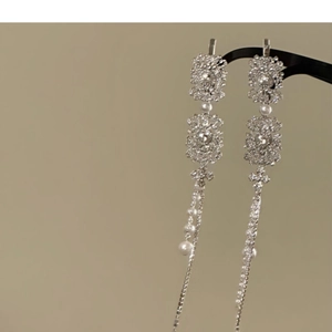 Macro detail of silver floral hair clips featuring tassel chains and white pearls