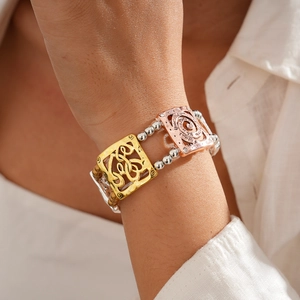 Detail of stacked bohemian elastic bracelets with hollow square patterns and mixed metal tones