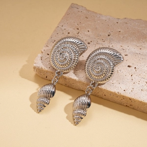 Detail of silver shell earrings with spiral texture on a natural stone background
