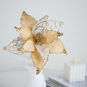 Champagne gold artificial Christmas flower with sequins on a white decorative pedestal