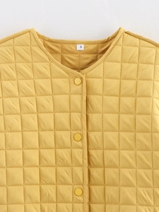Detail of yellow quilted cotton jacket featuring round neck and resin snap buttons