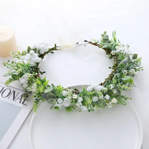 Detail of bridal floral headband with white flowers, green leaves and a tulle bow knot
