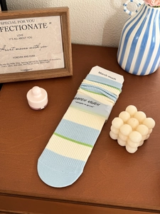 Detail of striped cotton crew socks with ribbed texture in cream, blue, and green tones