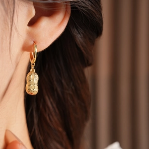 Detail of gold-plated peanut earrings with glass beads and a vintage textured finish