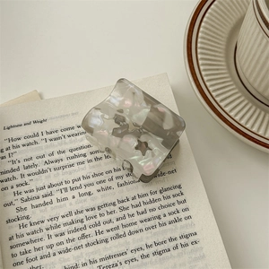 Detail of a pearlescent star patterned hair claw clip on an open vintage book