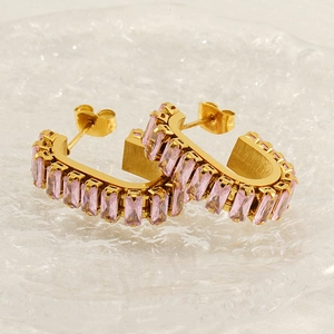 U-shaped gold earrings with pink rectangular zircon stones on a white textured backdrop