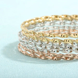 Makroaufnahme der geflochtenen Armreifen in Gold, Silber und Roségold-Finish