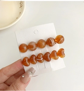 Detail of amber marble resin hair clips featuring heart and bead shapes on display card