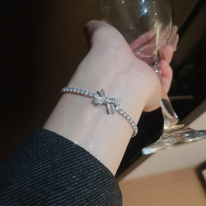 Sparkling silver bow bracelet with zircon stones worn on wrist for a luxury look