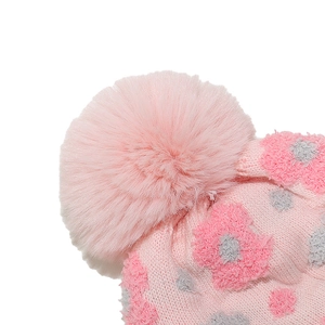 Detail of pink knitted girl's winter hat with fluffy faux fur pompom and flower texture
