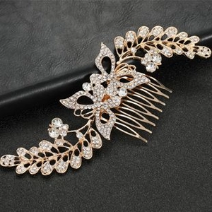 Detailed view of a gold metal hair comb with sparkling butterfly and leaf rhinestone patterns