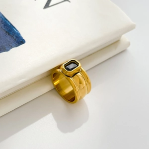 Macro shot of wide gold band ring featuring a rectangular black zircon and ridged texture