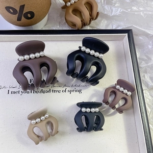 Brown plush hair claw clips with pearls shown in various sizes on a display board