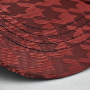 Macro detail of wine red houndstooth and star pattern on baseball cap brim with stitching