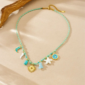 Bohemian colorful woven necklace with golden sun moon charms and sea star on sand background