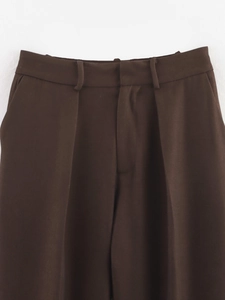 Detail of dark brown trousers waist with belt loops and textured woven fabric