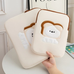 Detail of cute embroidered cartoon dog on plush cream-colored laptop and tablet sleeve set