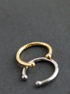 Macro shot of gold and silver C-shaped ear cuffs with 925 silver hallmark and bead ends