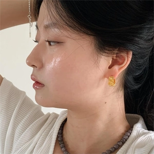 Detail view of gold textured hoop earrings with wrinkled surface on a fashion model