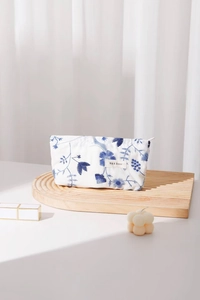 Détail de la trousse de maquillage en lin avec broderie florale bleue et étiquette de marque